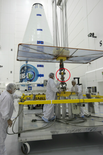 Technicians in clean suits prepare to lift a capsule holding a satellite